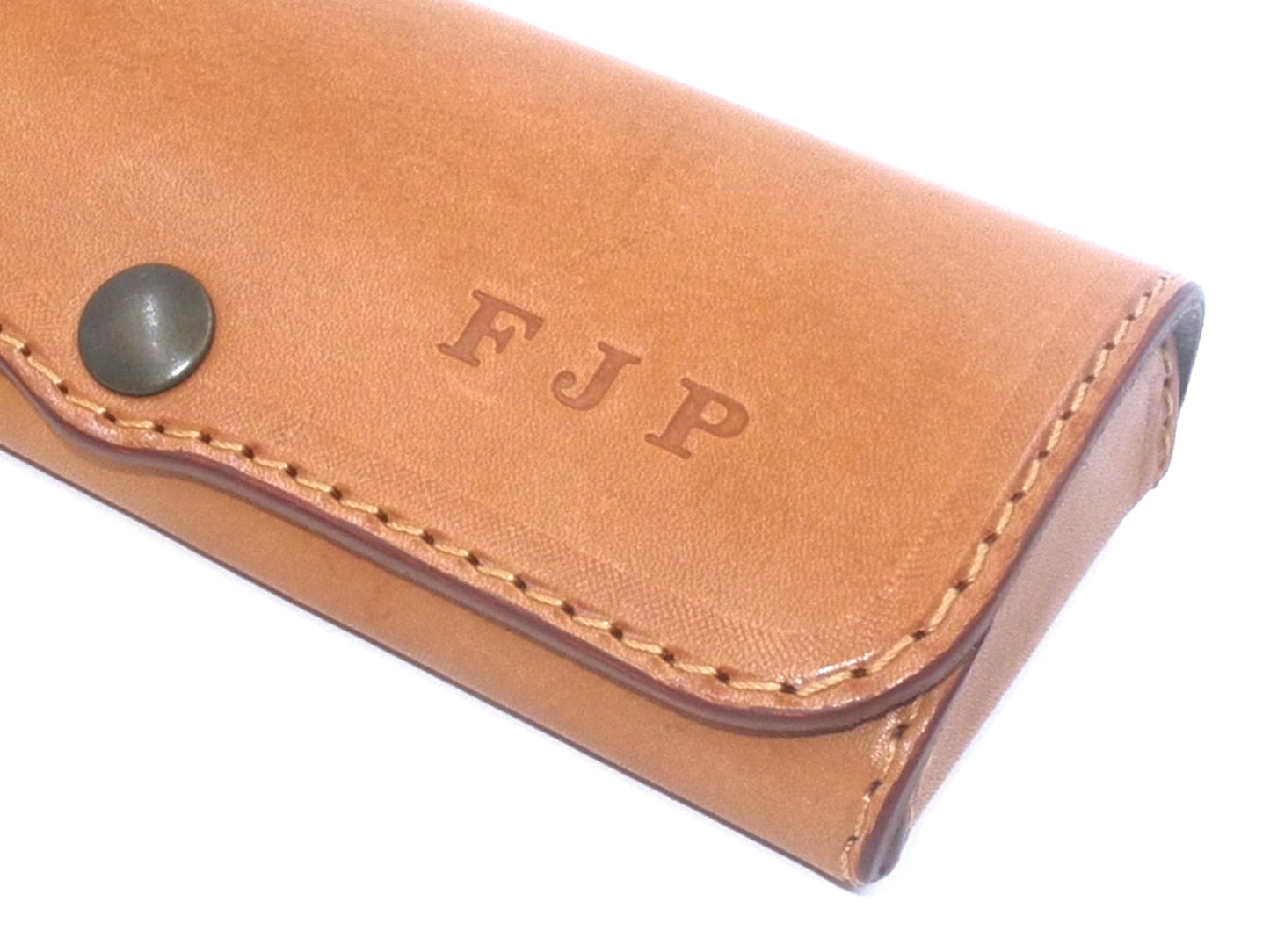 A light brown leather eyeglass case, partially seen from the side, showing how personalized it looks.