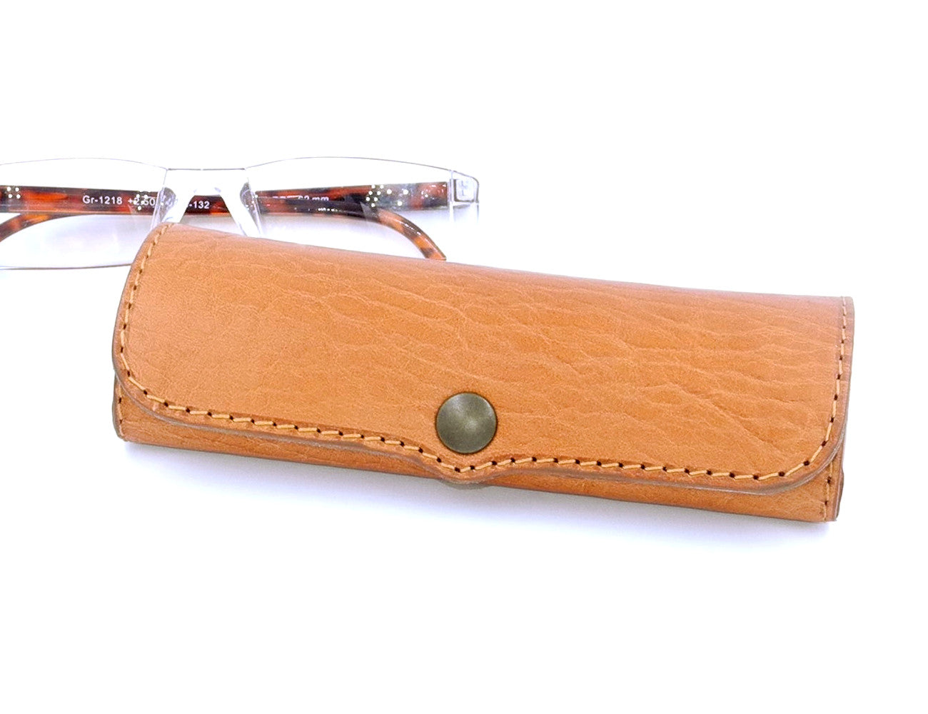 A light brown leather eyeglass case accompanied by a pair of reading glasses.