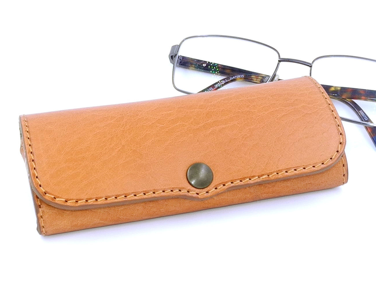 A light brown hard leather glasses case with a classic design, displayed alongside a pair of glasses to indicate use.